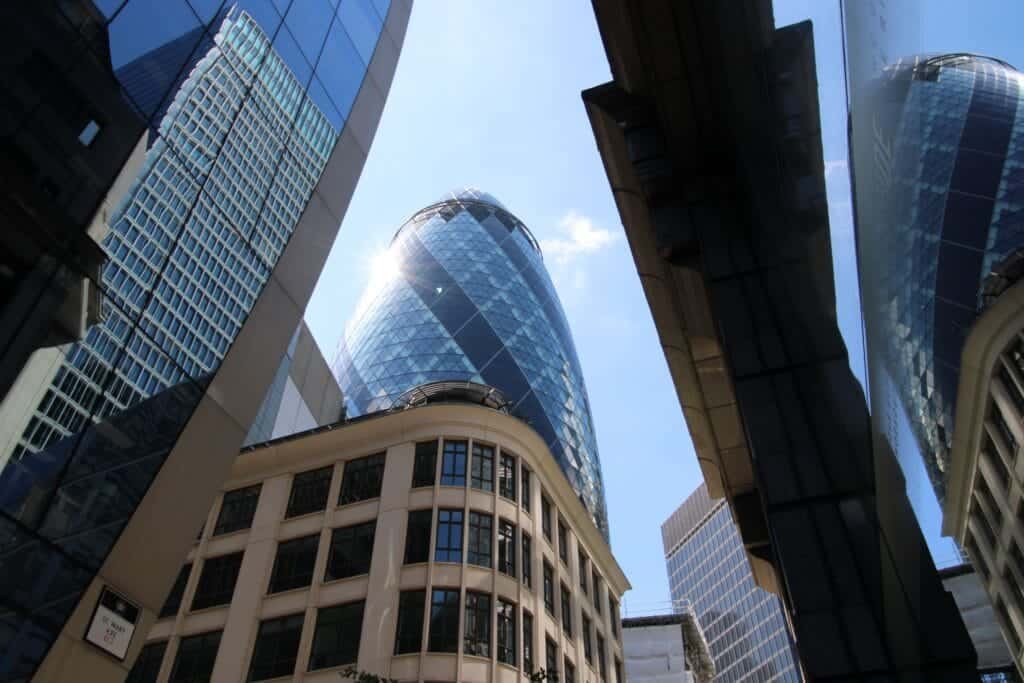 The Gherkin and modern buildings reflecting sunlight in London's financial district.